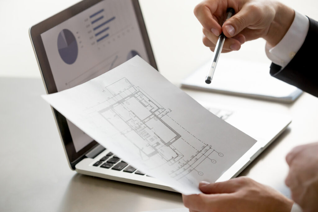 Male hand holding project plan, statistics on screen, close up